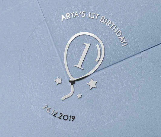Birthday stickers with a balloon graphic and personalized name and date printed in silver on a clear sticker