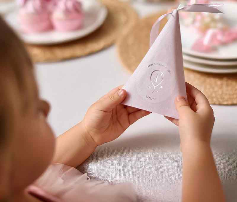 Girl holding party favour with a birthday sticker applied to it