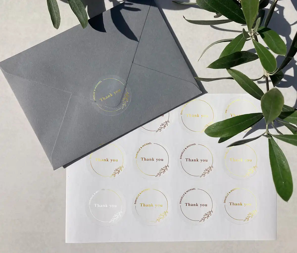 Wedding thank you sticker sheet with personalized names and delicate floral theme frame printed in gold on clear stickers