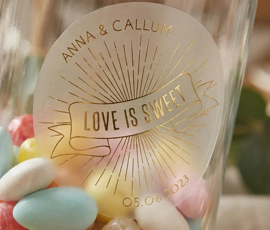 "Love is sweet" personalized wedding favour sticker printed in gold foil on transparent matte sticker and applied to a candy jar.