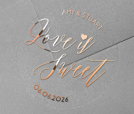 Love is sweet wedding favor sticker with heart graphic personalized names and date printed in rose gold on clear sticker