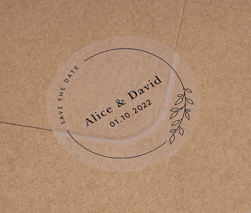 Save The Date sticker with personalised names and date and thin frame with leaves printed in black on clear round label