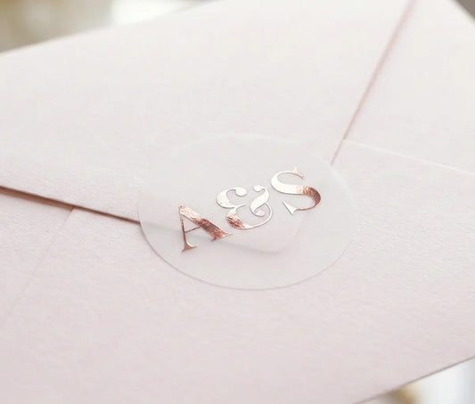 Pale Pink envelope with round Wedding envelope sticker with custom initials printed in rose gold foil on transparent matte vinyl.
