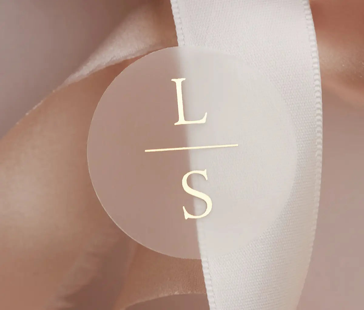 Personalized initials printed in gold foil on round clear sticker and applied to a wedding favour