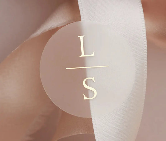 Personalized initials printed in gold foil on round clear sticker and applied to a wedding favour