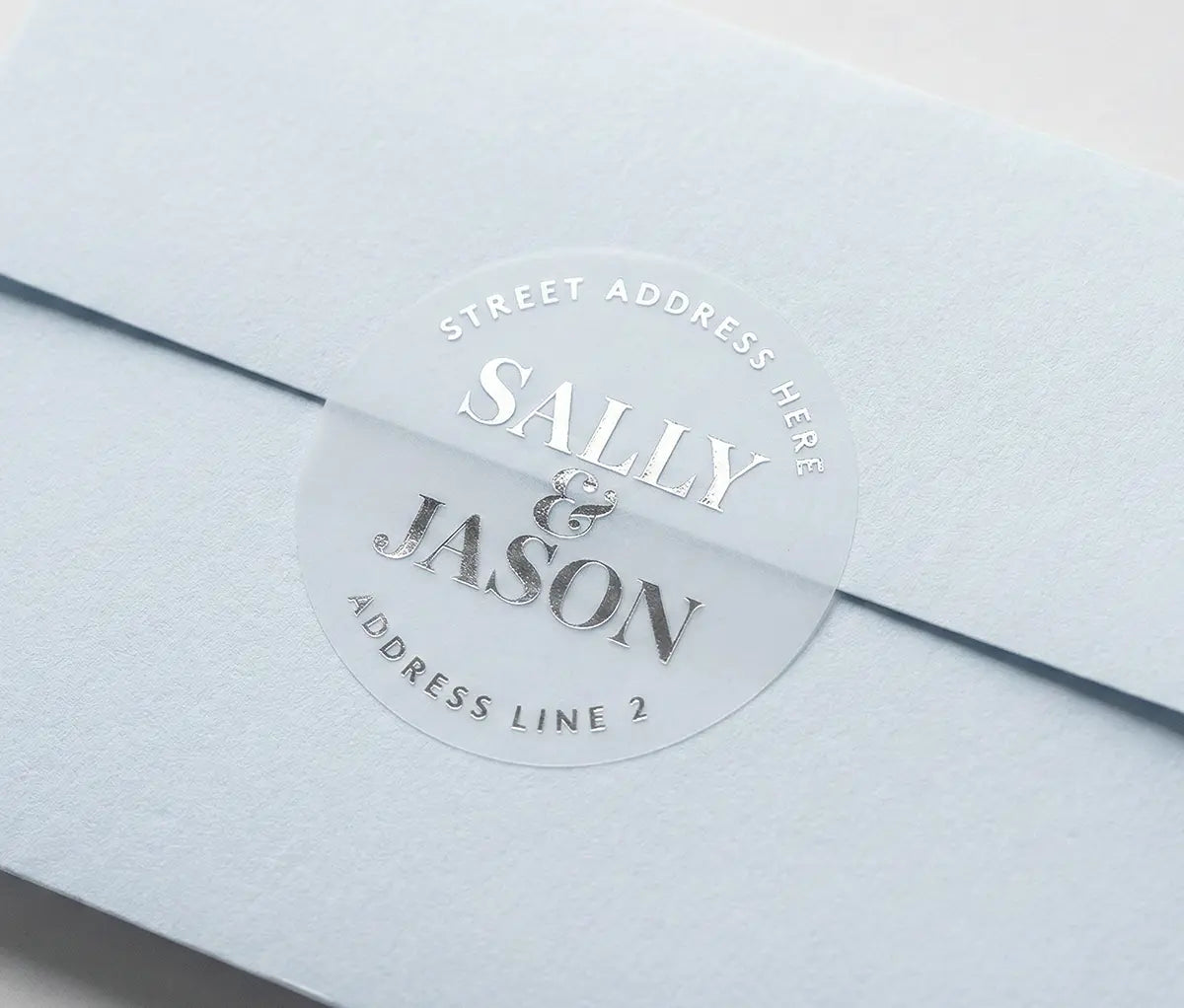 Light Blue envelope with round Retun Address Label printed in silver foil on transparent matte vinyl.