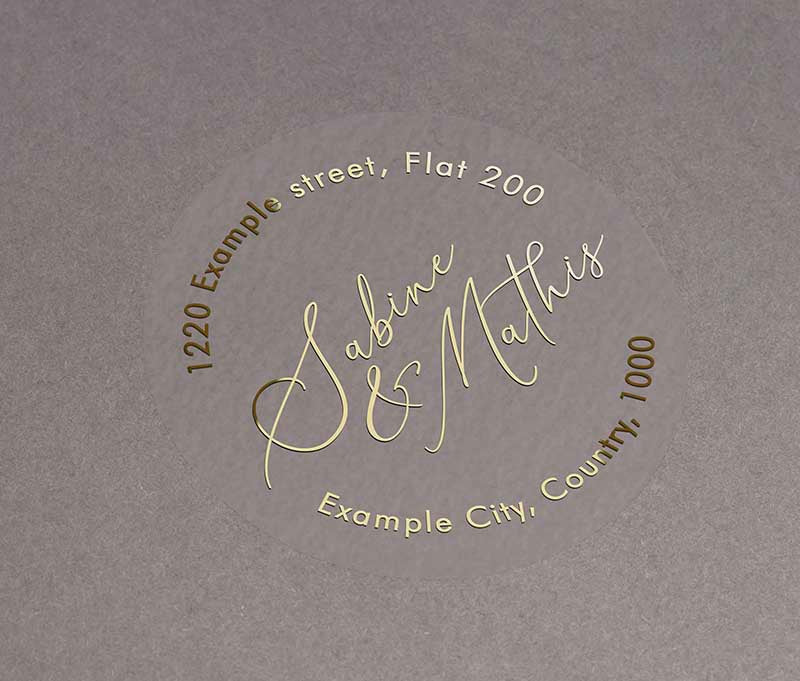Return address labels printed in gold on clear round sticker with names in calligraphy font