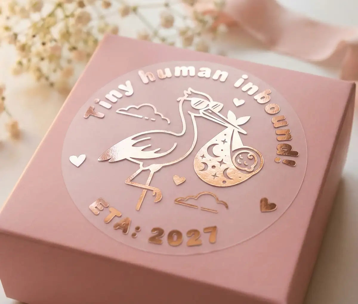 Personalized Stork baby shower sticker with custom year printed in rose gold and applied on a pink favour box.
