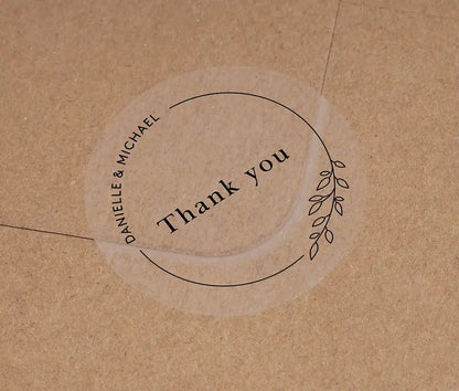 Wedding thank you sticker with personalized names and delicate floral theme frame printed in black on clear sticker