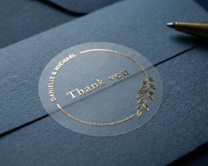 Wedding thank you sticker with personalized names and delicate floral theme frame printed in gold on clear sticker