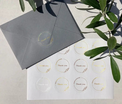Wedding thank you sticker sheet with personalized names and delicate floral theme frame printed in gold on clear stickers