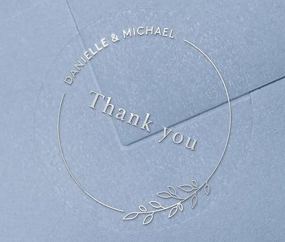 Wedding thank you sticker with personalized names and delicate floral theme frame printed in silver on clear sticker
