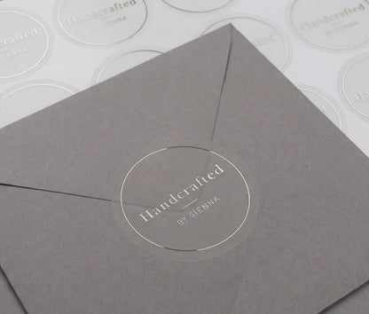 "Handcrafted" business sticker is printed in silver foil and applied to a grey envelope. There is a sticker sheet behind the envelope.