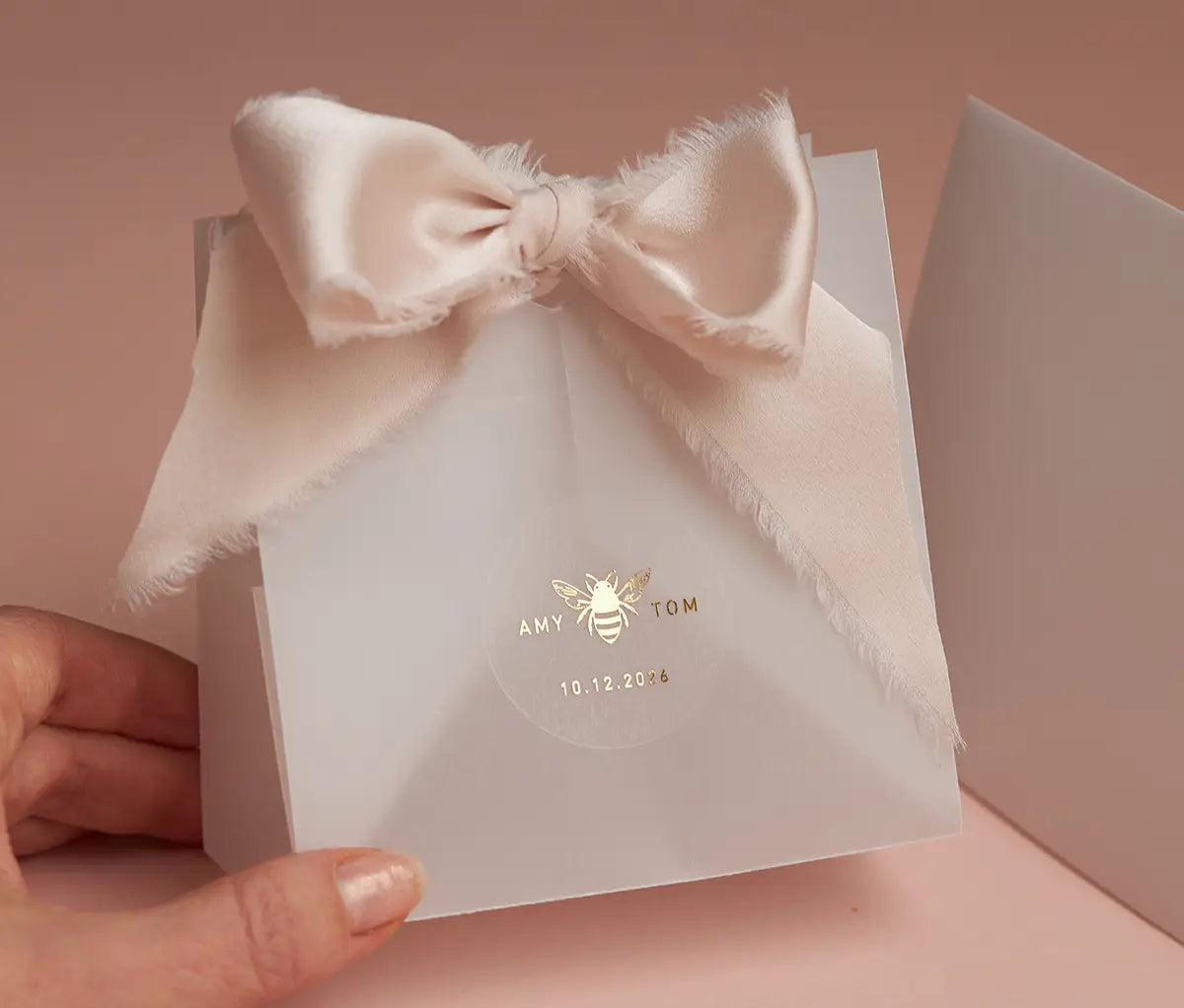 Honey bee graphic and personalized names printed in gold on round clear sticker and applied to a favor packaging
