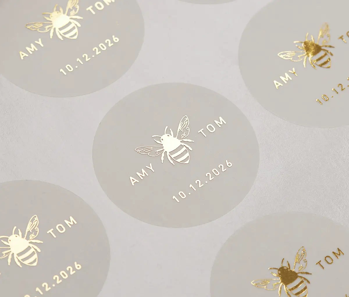 Honey bee graphic and personalized names printed in gold on round clear sticker sheet