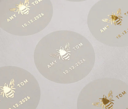 Honey bee graphic and personalized names printed in gold on round clear sticker sheet