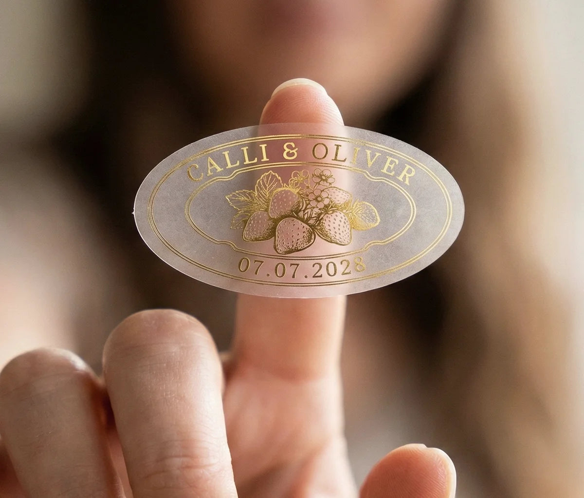 Frosted oval personalized strawberry jam label with strawberry graphic, couples names and date printed in gold foil.