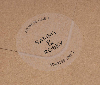 Return address labels with black printing on clear round labels, applied to an envelope.