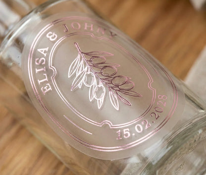 Glass bottle with personalized oval frosted sticker featuring olive graphic printed in pale pink foil.