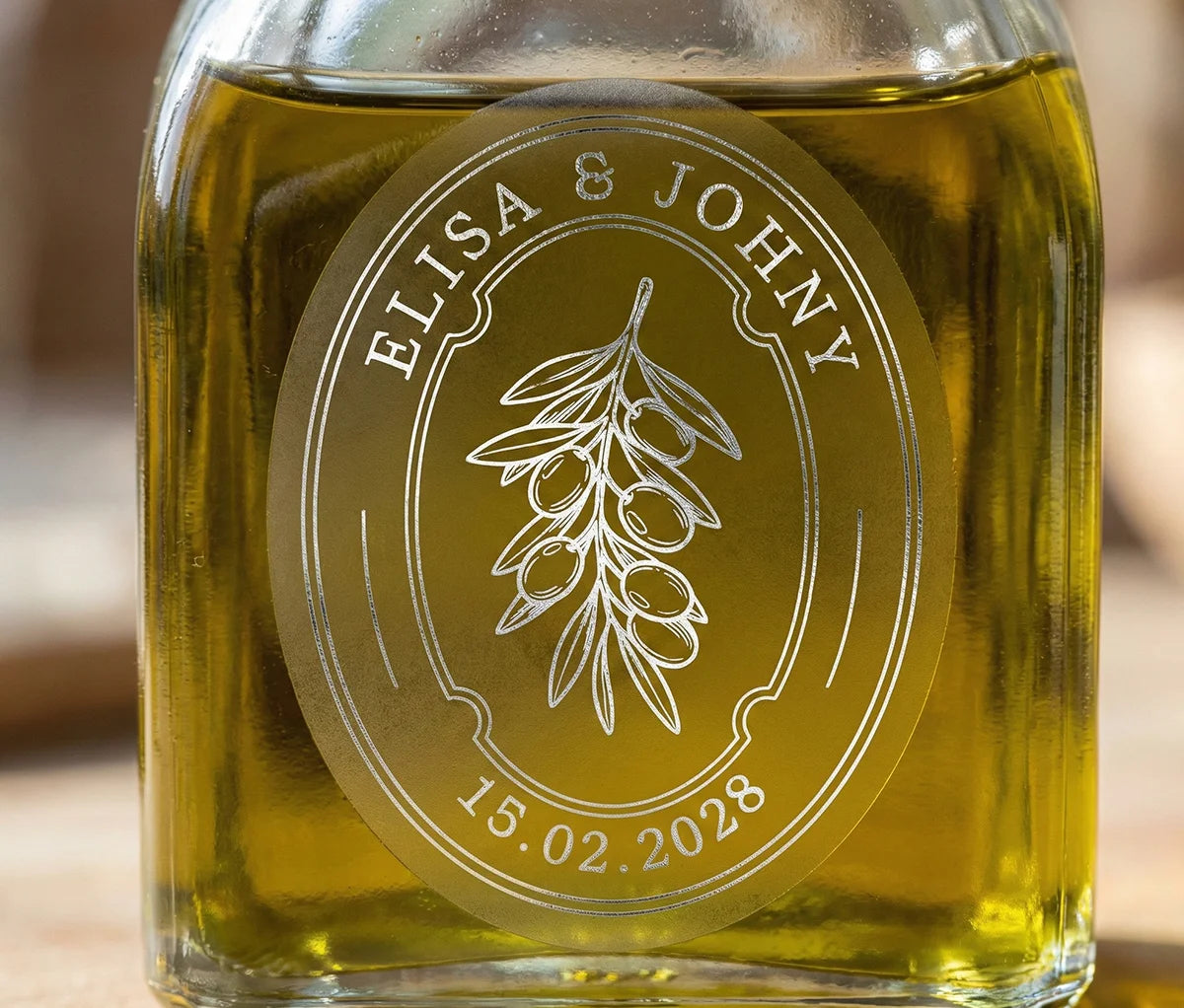 Glass bottle of olive oil with personalized oval frosted sticker printed in silver foil.