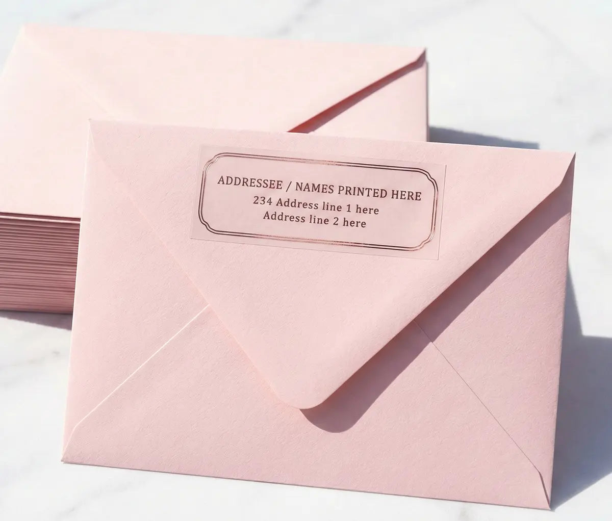 Pink envelope with wedding return address label printed in rose gold foil on transparent vinyl.