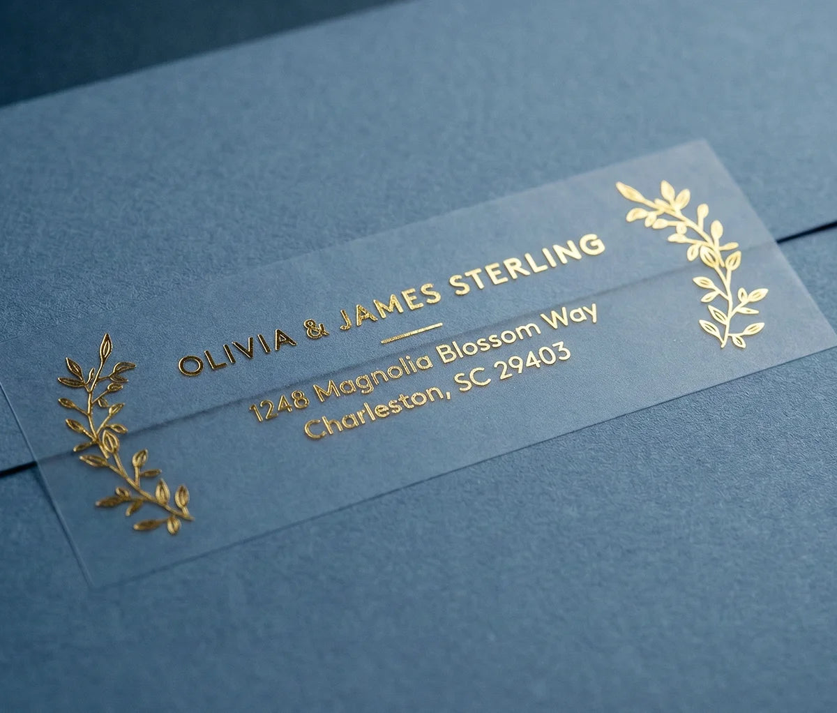 Return Address Label with Laurel Leaf Motif printed in gold foil on transparent matte labels applied to a blue envelope.