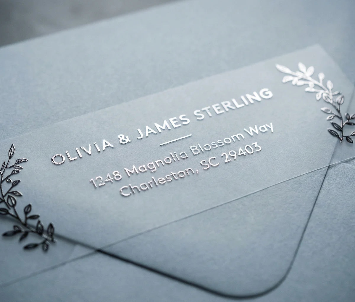 Return Address Label with Olive Leaf Motif printed in silver foil on transparent matte labels applied to a grey envelope.
