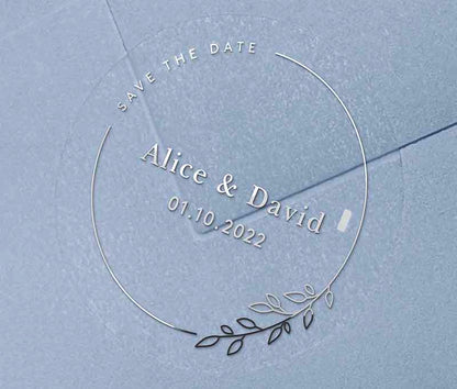 Save The Date sticker with personalised names and date and thin frame with leaves printed in silver on clear round label