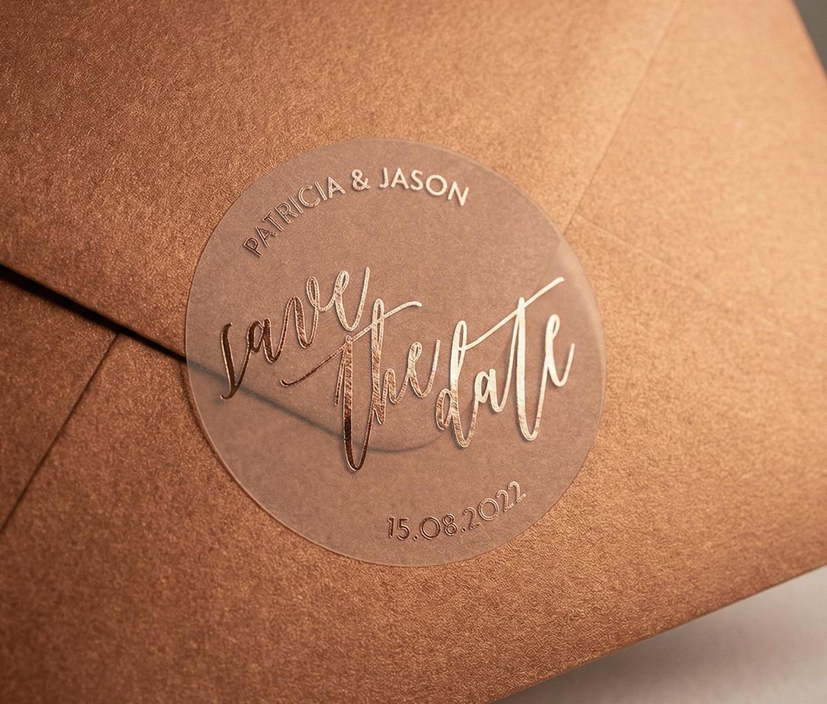 Bronze colour envelope with a clear 'save the date' sticker featuring custom names and date printed in rose gold foil.