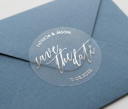 Navy blue envelope with a clear 'save the date' sticker featuring custom names and date printed in silver foil.