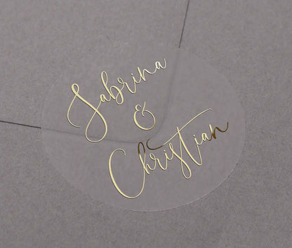 Wedding favor stickers with personalized names printed in gold foil on clear round sticker