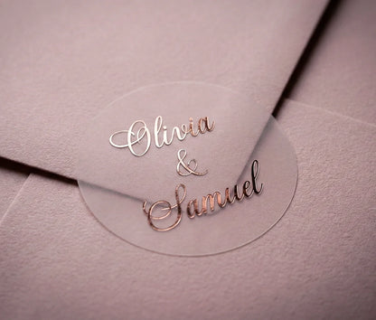 Round clear label with custom names printed in rose gold applied to a dusty pink envelope.