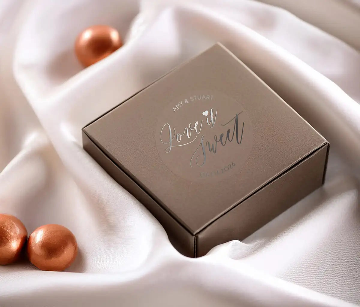 Love is sweet wedding favor sticker with heart graphic personalized names and date printed in silver and applied to a small box