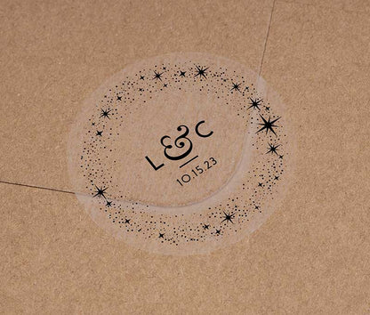 Celestial wedding favor stickers with stars around personalized initials and date printed in black on clear sticker