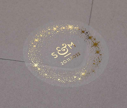 Celestial wedding favor stickers with stars around personalised initials and date printed in gold on clear sticker