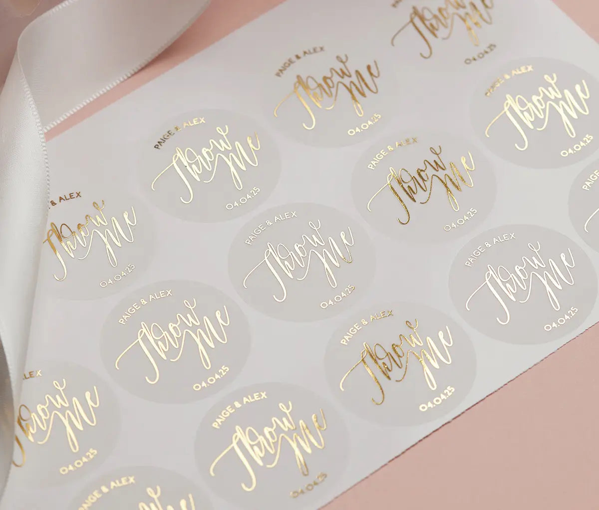 A sheet of personalized wedding stickers with the custom names, a date, and the text 'throw me' printed in gold foil.