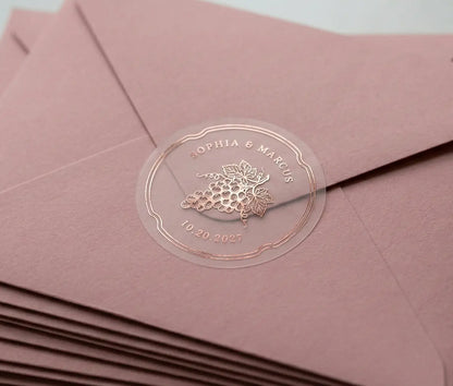 Vineyard theme wedding envelope stickers with custom names and date printed in rose gold foil and used to seal pink envelope.
