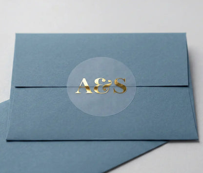 Blue envelope with round Wedding envelope seal with custom initials printed in gold foil on transparent matte vinyl.