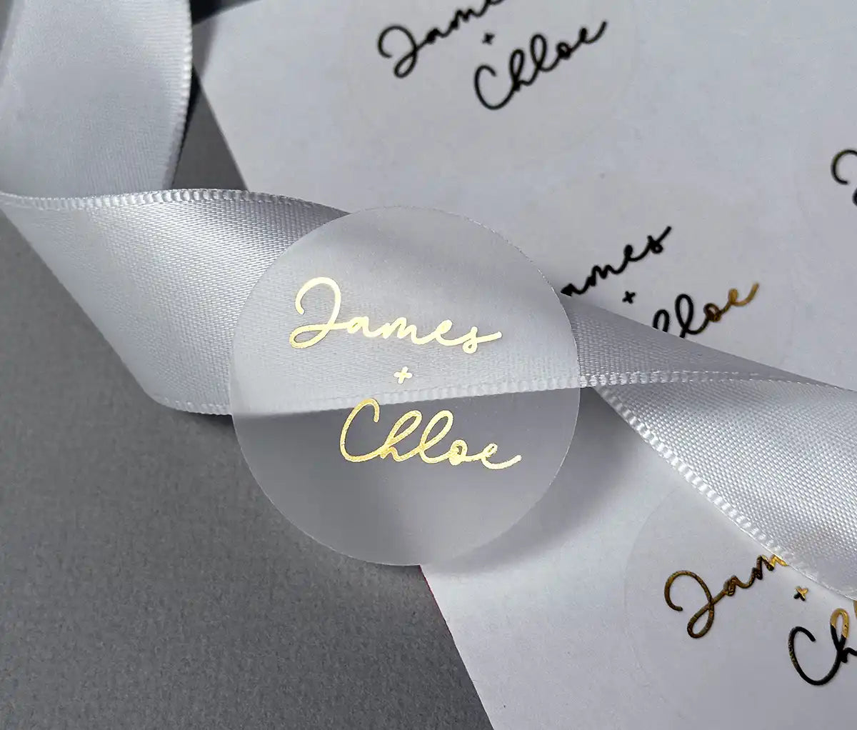 Personalized names in script font and plus sign printed in gold on clear wedding envelope sticker