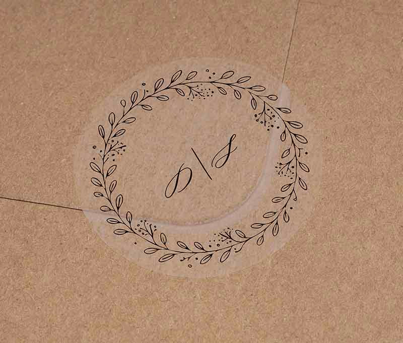 Wedding envelope sticker with wreath graphic and personalized initials printed in black ink.