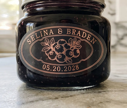 Oval personalized rose gold foil print matte wedding favour label on a blueberry jam jar.