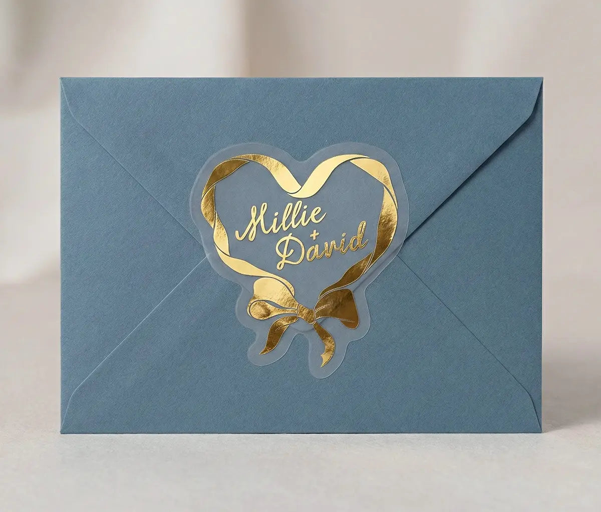 Blue envelope sealed with gold heart and bow design sticker.