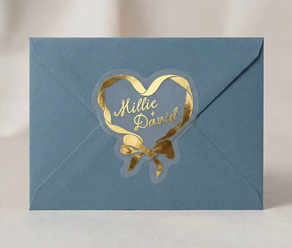 Blue envelope sealed with gold heart and bow design sticker.