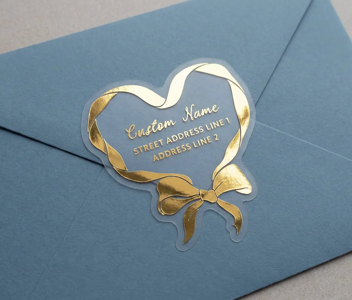 Gold bow-shaped cute return address label on a blue envelope