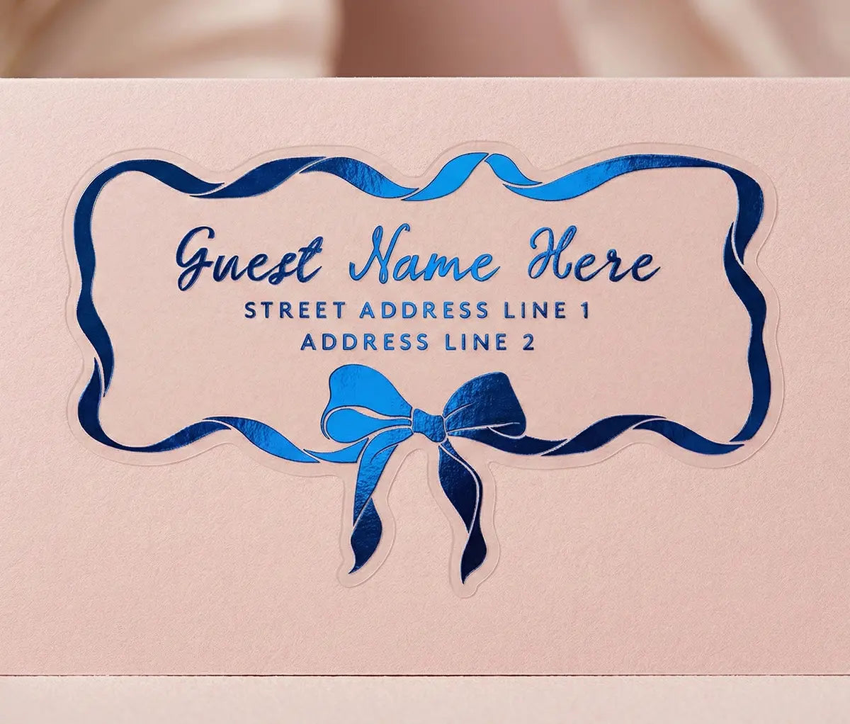 Personalized recipient address label with blue ribbon and bow design on a pale pink envelope.