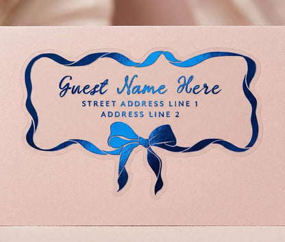 Personalized recipient address label with blue ribbon and bow design on a pale pink envelope.
