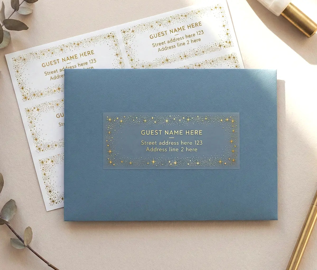 Guest address label with celestial theme frame printed in gold foil on transparent label and applied to a slate blue envelope.