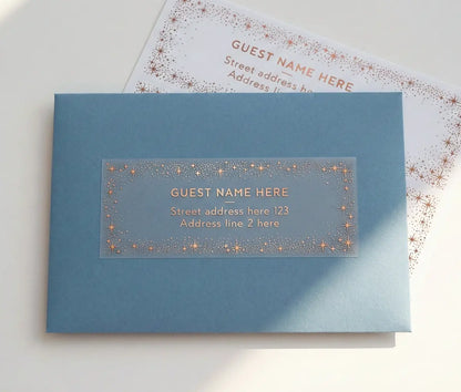 Guest address label with starry frame printed in rose gold foil applied to a slate blue envelope.