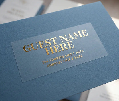 Custom Guest address sticker featuring bold typography printed in gold foil on transparent matte vinyl and applied to a blue envelope.