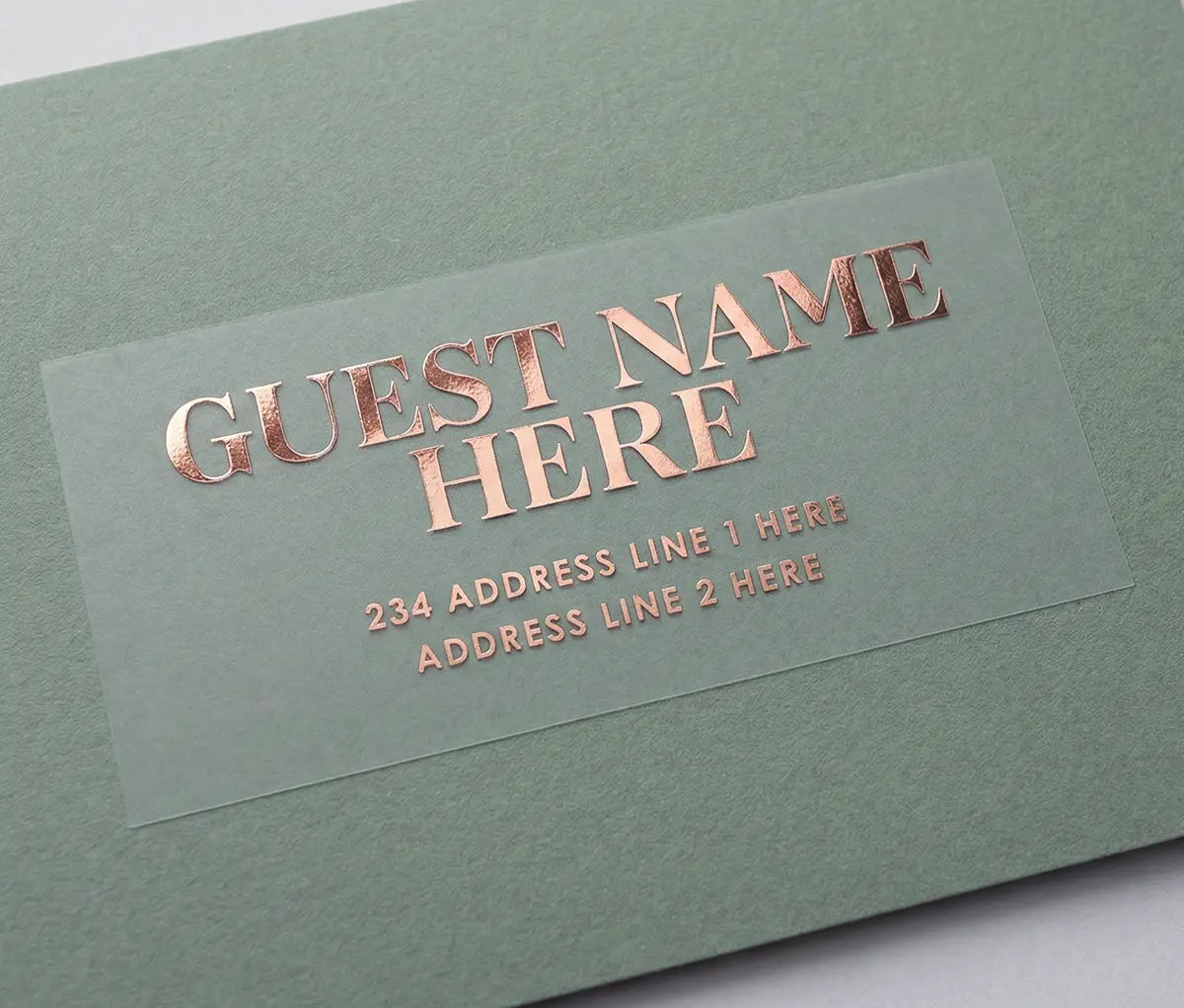 Custom Guest address sticker featuring bold serif font printed in rose gold foil on transparent matte vinyl and applied to a sage green envelope.
